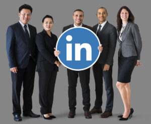 Cinco executivos, entre homens e mulheres, seguram o símbolo do Linkedin, demonstrando que o Linkedln funciona para encontrar trabalho