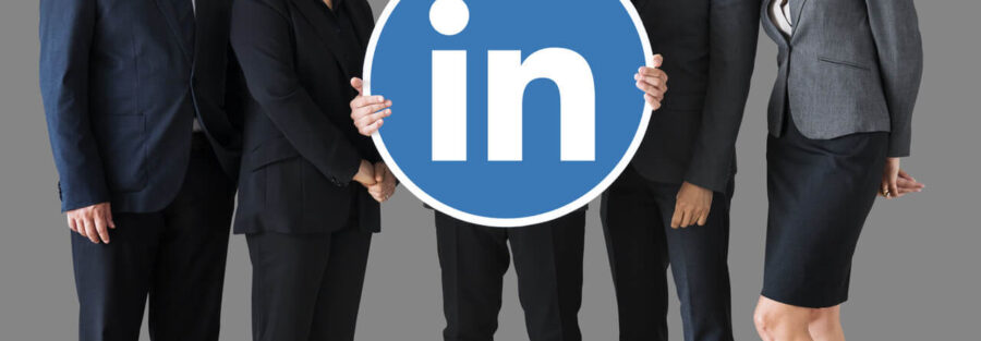 Cinco executivos, entre homens e mulheres, seguram o símbolo do Linkedin, demonstrando que o Linkedln funciona para encontrar trabalho