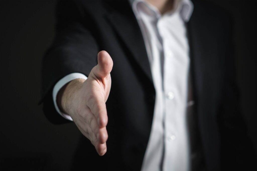 Homem estende a mão para cumprimentar o recrutador após conseguir a recolocação profissional de executivo