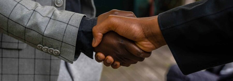 Imagem focando um aperto de mão entre dois homens, contextualizada para artigo sobre empresa de recolocação profissional.