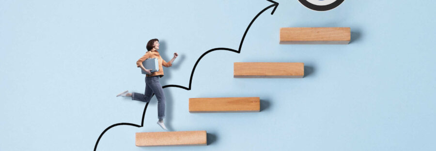 Mulher sobe degraus mostrando de que forma podemos elaborar um plano de carreira. Imagem: Freepik