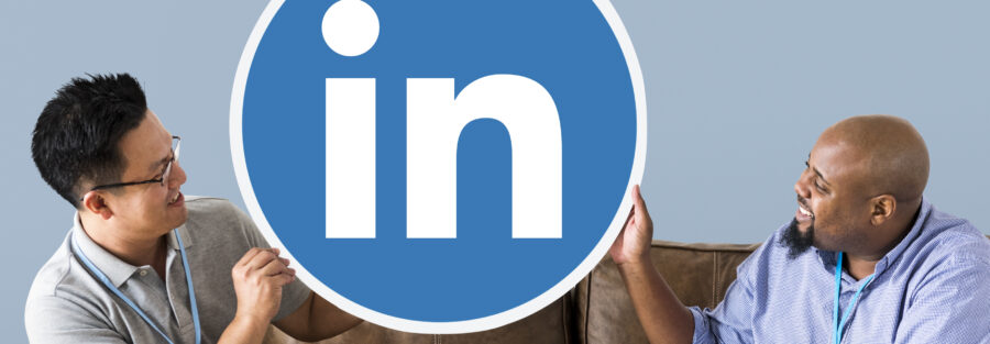 Imagem de dois homens segurando um círculo com o ícone do LinkedIn para ilustrar artigo sobre como criar um perfil no LinkedIn. Imagem: Freepik.