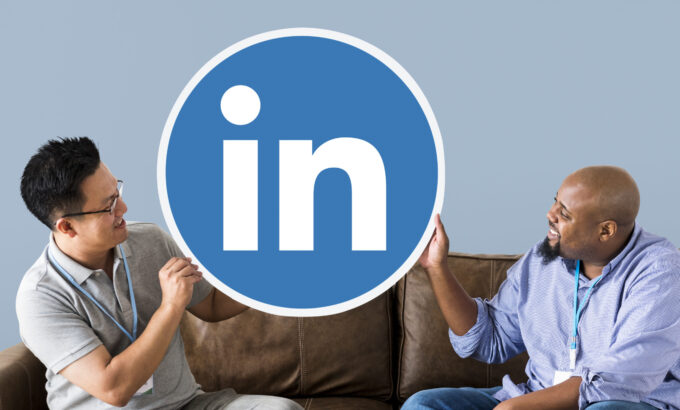 Imagem de dois homens segurando um círculo com o ícone do LinkedIn para ilustrar artigo sobre como criar um perfil no LinkedIn. Imagem: Freepik.