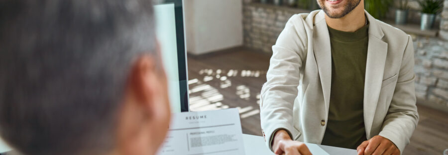 Imagem de dois homens apertando as mãos durante uma entrevista de emprego para ilustrar artigo sobre recolocação no mercado de trabalho. Foto: Freepik