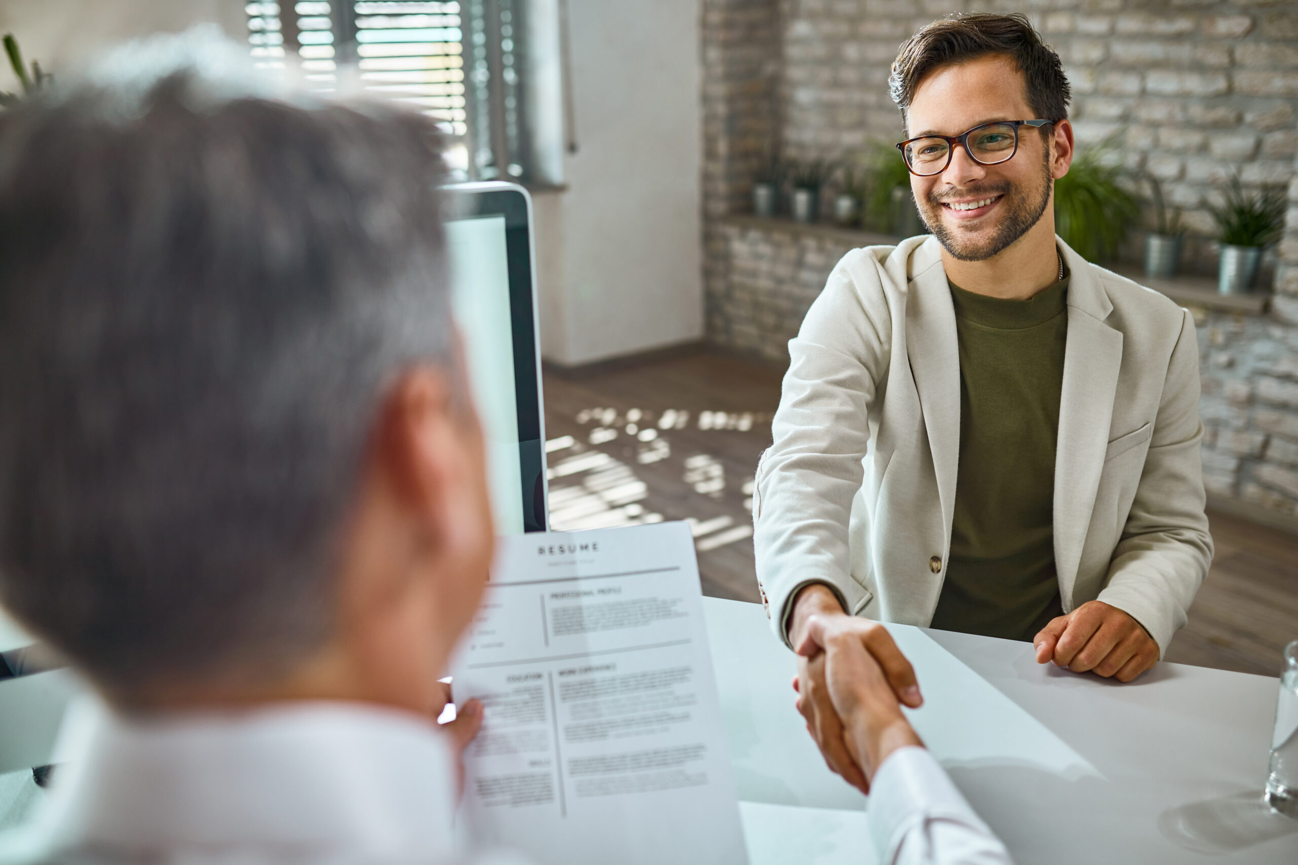 Imagem de dois homens apertando as mãos durante uma entrevista de emprego para ilustrar artigo sobre recolocação no mercado de trabalho. Foto: Freepik